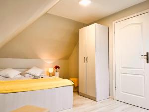 a small attic bedroom with a bed and a white cabinet at Mazurska Chatka in Srokowo