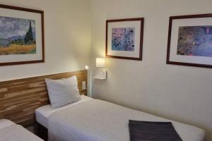 a room with two beds and two pictures on the wall at Margarida Guest House - Lisbon South by Rosado in Almada