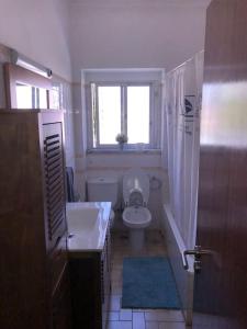 a bathroom with a toilet and a sink and a window at Margarida Guest House in Almada