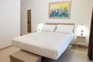 a white bedroom with a white bed and a painting at Ruffini Rooms in Termoli