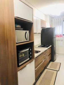a kitchen with a microwave and a stove and refrigerator at Praia de Palmas, Residencial Anito Petry! in Governador Celso Ramos