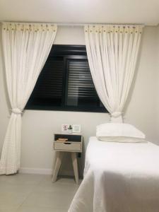 1 dormitorio con 1 cama y una ventana con cortinas en Praia de Palmas, Residencial Anito Petry!, en Governador Celso Ramos
