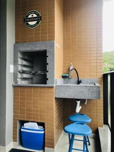 a kitchen with two blue stools under a sink at Praia de Palmas, Residencial Anito Petry! in Governador Celso Ramos