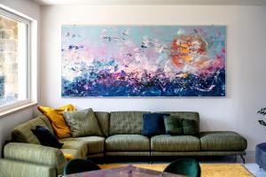 OLIVETO A MARE - Suite & Apartment في أسشيا: غرفة معيشة مع أريكة ولوحة على الحائط