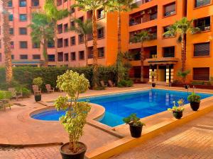 a swimming pool in front of a building with palm trees at Apparts KARAMI in Marrakesh