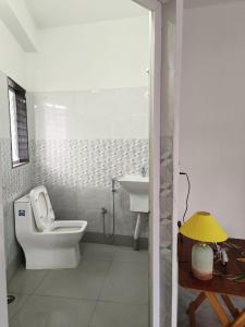 a white bathroom with a toilet and a sink at Traveller's Nest in Siliguri