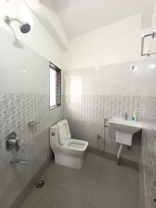 Baño blanco con aseo y lavamanos en Traveller's Nest en Siliguri