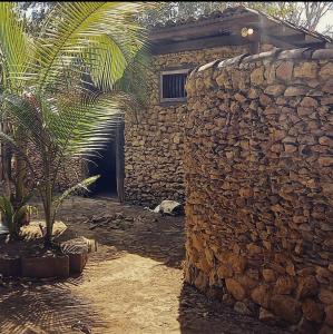 a stone house with a stone wall and a palm tree at Villas del Mar Hostal in Cañas