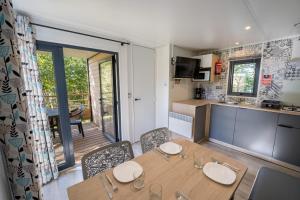 a kitchen and dining room with a table and chairs at Flower Camping La Sténiole in Granges-sur-Vologne +22 photos
