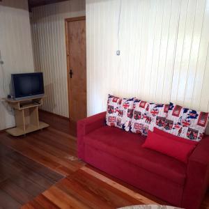 - un salon avec un canapé rouge et une télévision dans l'établissement Casa D&R, à Canela