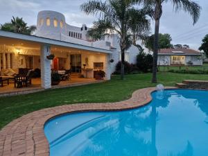 a swimming pool in front of a house at Villa Sardinia Guest House in Midrand