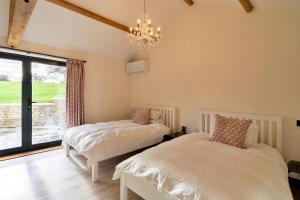 a bedroom with two beds and a chandelier at Finest Retreats - The Stables at Lilac Cottage in Hawling