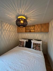 1 dormitorio con cama blanca y lámpara de araña en Camping 't Venhop, en Berkhout
