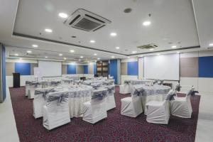 a banquet hall with white tables and chairs and a screen at Hotel Bluestone - Nehru Place in New Delhi