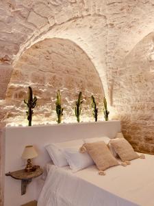 1 dormitorio con 1 cama en una pared de piedra en Dimore i Messapi Suites, en Ceglie Messapica