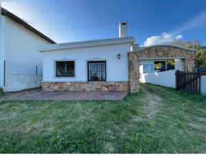 a white house with a gate and a yard at Casa Alquiler Cuchilla Alta 1 in Cuchilla Alta