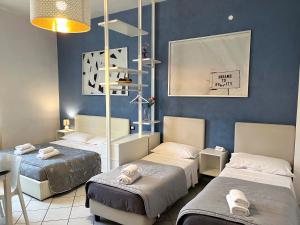 um quarto com três camas e uma parede azul em La Suite Rooms & Apartments em Bolonha
