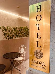 Amdar Hostel في إيلات: لافته للفندق وطاولة وكرسي
