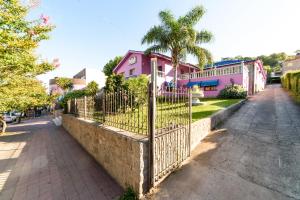 a fence in front of a pink house with a palm tree at Hotel de France Rio Ceballos in Río Ceballos