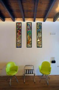 a room with three chairs and four stained glass windows at Casa vacanze Santa Marta in Barletta