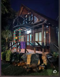 una casa de madera con porche por la noche en Complejo Cascadas de Artalaz en Colón
