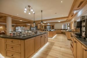 a large kitchen with wooden cabinets and black counter tops at Wohlfühlhotel KERSCHDORFER - B&B - ADULTS ONLY in Kaltenbach