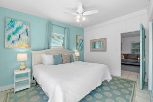 een slaapkamer met een wit bed en blauwe muren bij Aquaverde Beach House in Pensacola Beach