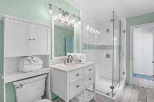 een witte badkamer met een wastafel en een douche bij Aquaverde Beach House in Pensacola Beach +45 foto's