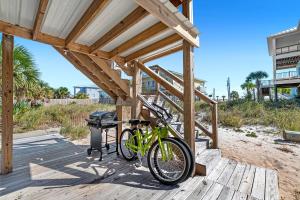 twee fietsen geparkeerd onder een houten constructie op het strand bij Aquaverde Beach House in Pensacola Beach