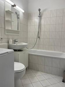 a bathroom with a toilet and a sink and a bath tub at Gemütlichkeit mit Cityblick in Leipzig