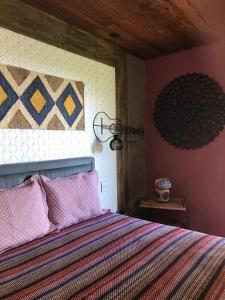 a bedroom with a bed with pink and colorful sheets at Macondo Chalés in Lavras Novas +278 photos
