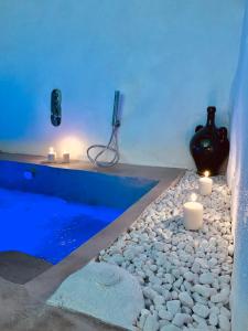 una bañera con velas y un jarrón sentado en un suelo de guijarros en Dimore i Messapi Suites, en Ceglie Messapica