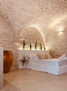 una camera da letto con un letto bianco in un muro di mattoni di Dimore i Messapi Suites Diffuse a Ceglie Messapica