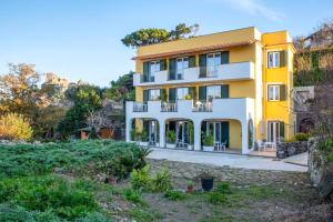 a yellow and white house with a yard at B&B La Vigna Rooms - Ischia Ponte in Ischia