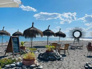 een strand met parasols en stoelen en de oceaan bij Beachfront apartment - terrace with sea view - pool in Algarrobo