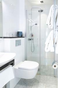 a white bathroom with a toilet and a shower at Continental du Sud in Ystad