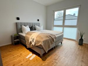 a bedroom with a bed and a large window at Luxus-Ferienhaus mit Saunen und großem Garten in Göhren-Lebbin