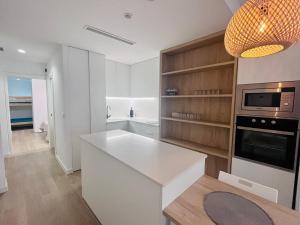 cocina con encimera blanca y microondas en Planta baja a 50 metros de la playa, en El Perelló