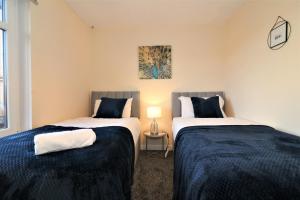 two beds in a small room with a lamp at Signature - Shield House in Scotstoun