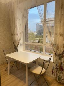 a table and chairs in a room with a window at ЖК Чемпион in Taldykolʼ