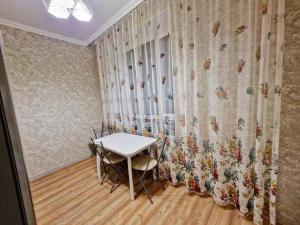 a table and chairs in a room with a curtain at ЖК Чемпион in Taldykolʼ