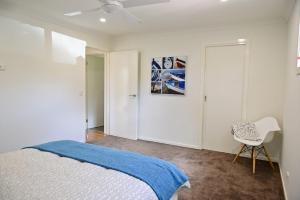 a bedroom with a bed and a white chair at 7 Gilmore Street, Smiths Beach in Smiths Beach