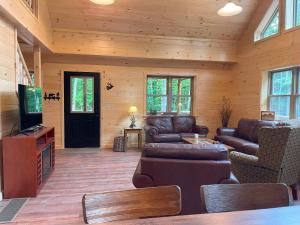 a living room with leather furniture and a flat screen tv at Blissful Bear in Old Forge