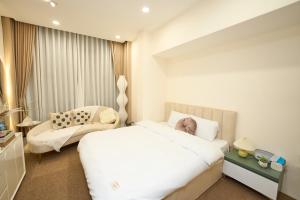 - une chambre avec un grand lit blanc et une chaise dans l'établissement EDEN RESIDENCE, à Hanoï