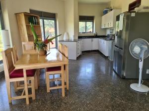 a kitchen with a table and a refrigerator and a fan at Nile retreat in Jinja