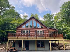 a log cabin with a deck on top of it at Blissful Bear in Old Forge