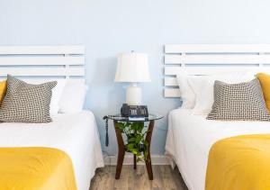 two beds with white and yellow sheets and a table with a lamp at Arawak Bay: Inn at Salt River in Christiansted