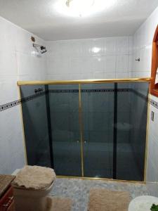 y baño con ducha de cristal y aseo. en Casa Ipê en Monte Verde