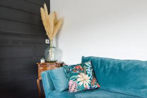a blue couch with a pillow and a vase on a table at Gîte chalet 12 pers Spa Hautes Vosges Les Libellules in Fresse-sur-Moselle