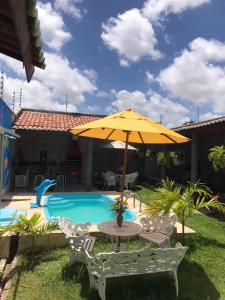 een tafel met een parasol naast een zwembad bij Recanto Girassol in Aquiraz